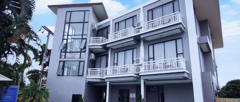 A modern building with a pool, multiple balconies, and outdoor seating.
