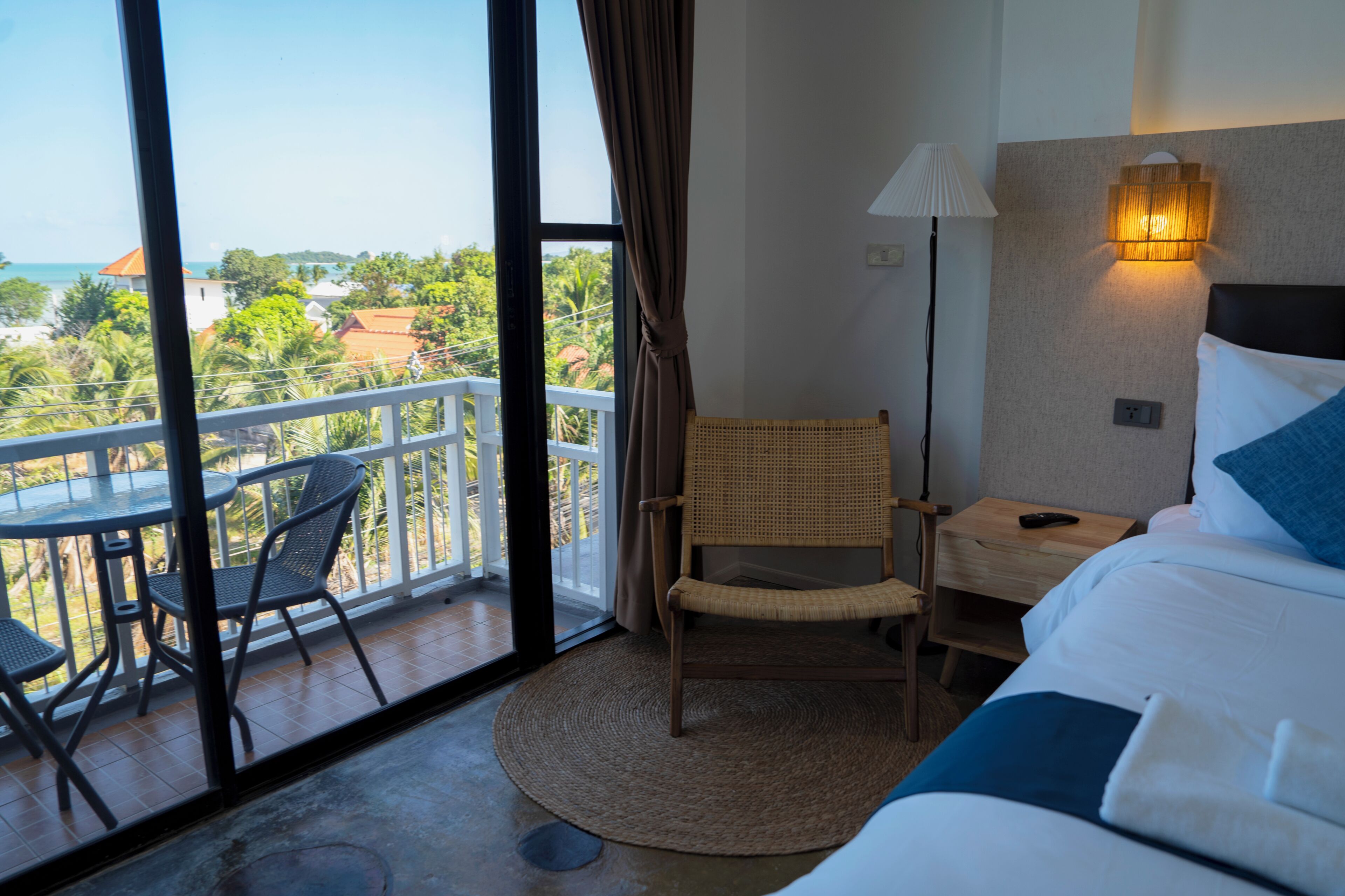 Una habitación de hotel con balcón, cama, silla y mesita de noche.