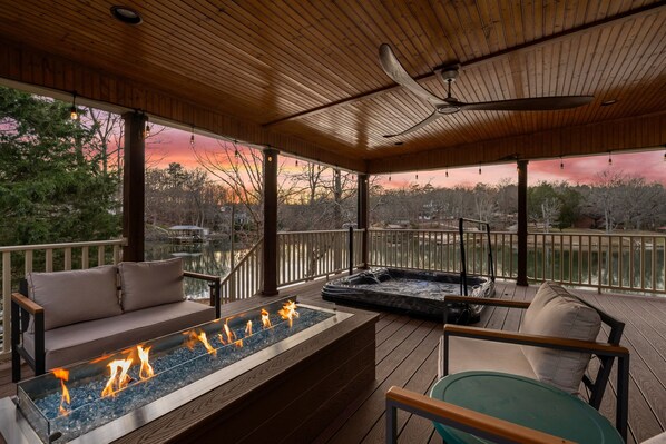 A wooden deck with a fire feature, seating, and a hot tub.