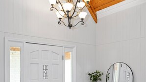 Una habitación con techo de madera, una puerta blanca, un espejo y una pequeña mesa con una planta y un cuenco.
