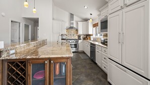 Una cocina moderna con armarios blancos, encimera de granito y electrodomésticos de acero inoxidable.