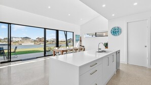 A modern kitchen with a large island, a view of a lake, and a dining area with chairs.