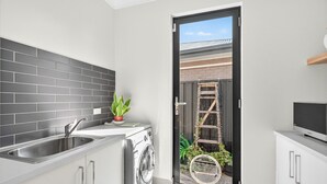 A compact kitchen with a built-in washing machine, a sink, and a potted plant.