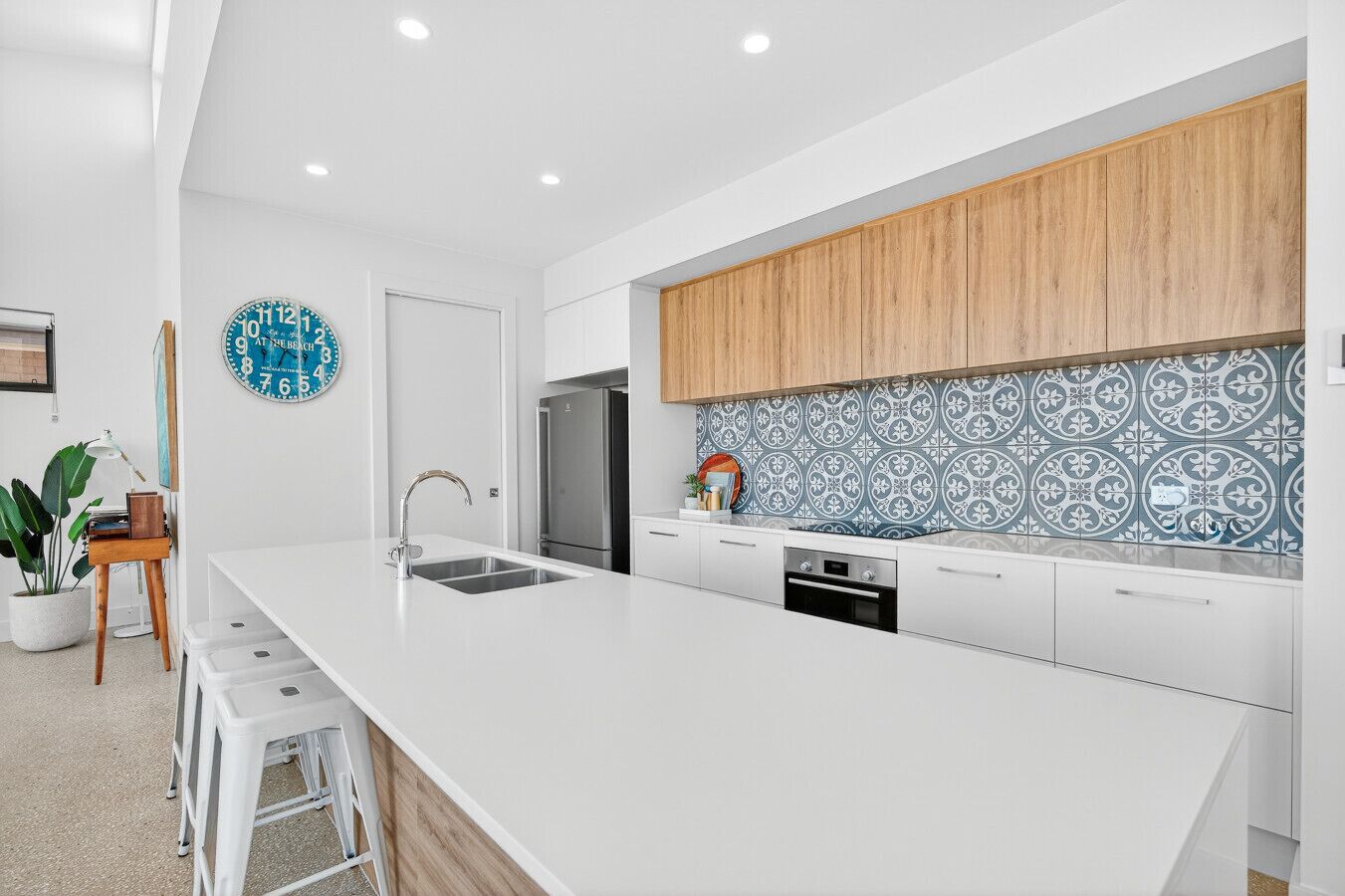 A modern kitchen with a large island, white cabinetry, and a decorative backsplash.