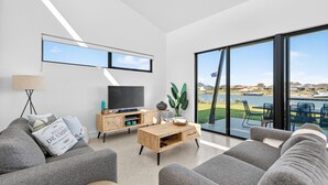 A modern living room with a large window, a flat-screen TV, and a wooden coffee table.