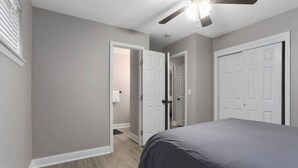 Ein Schlafzimmer mit einem Bett, einem Deckenventilator und zwei weißen Türen.