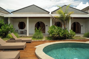 Un resort con piscina, sillas de descanso y un área de terraza techada.