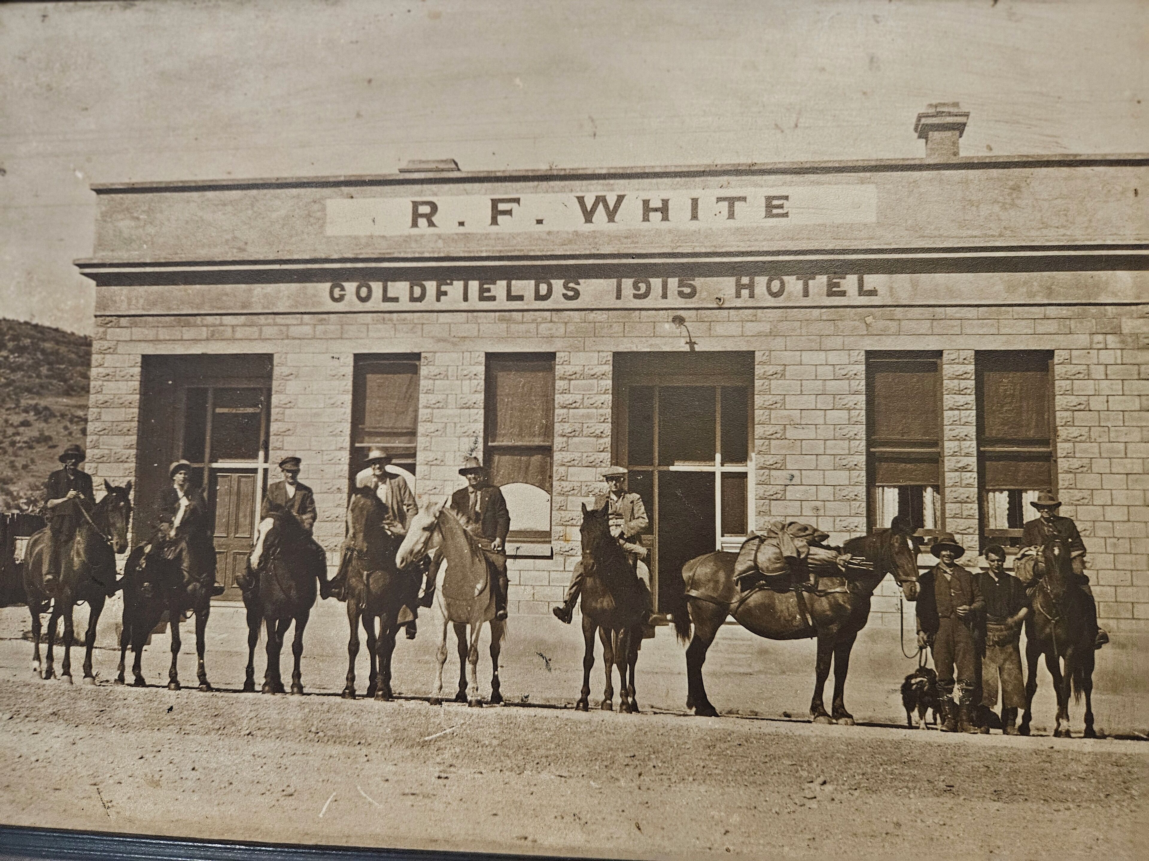 A building labeled "R.F. White Goldfields 1915 Hotel" with a brick facade and large windows.