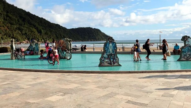 A swimming pool with a tiled deck, surrounded by people and bicycles. - Badaró's Beach Relax near the beach, 5 minutes from Mallet, shopping, and pet-friendly. (Praia Grande)