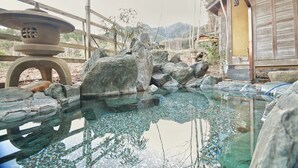 Un jardín japonés tradicional con un estanque sereno, rocas grandes y una valla de madera.