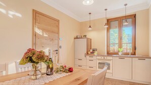 A kitchen with a wooden table, white cabinets, and a window with a view of greenery.