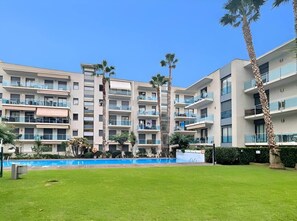 A multi-story residential building with balconies, a swimming pool, and palm trees. - Relax in Lloret with Fitness & Pool by Host&Joy (Lloret De Mar)