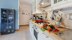 A modern kitchen with a gas stove, white cabinets, and a blue cabinet with dishes. - Blu Oltrelago: Leggiuno Lake Maggiore Apt w/ Shared Pool & Garden, Leggiuno, Italy (Leggiuno)