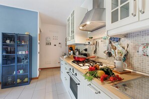 A modern kitchen with a gas stove, white cabinets, and a blue cabinet with dishes. - Blu Oltrelago: Leggiuno Lake Maggiore Apt w/ Shared Pool & Garden, Leggiuno, Italy (Leggiuno)