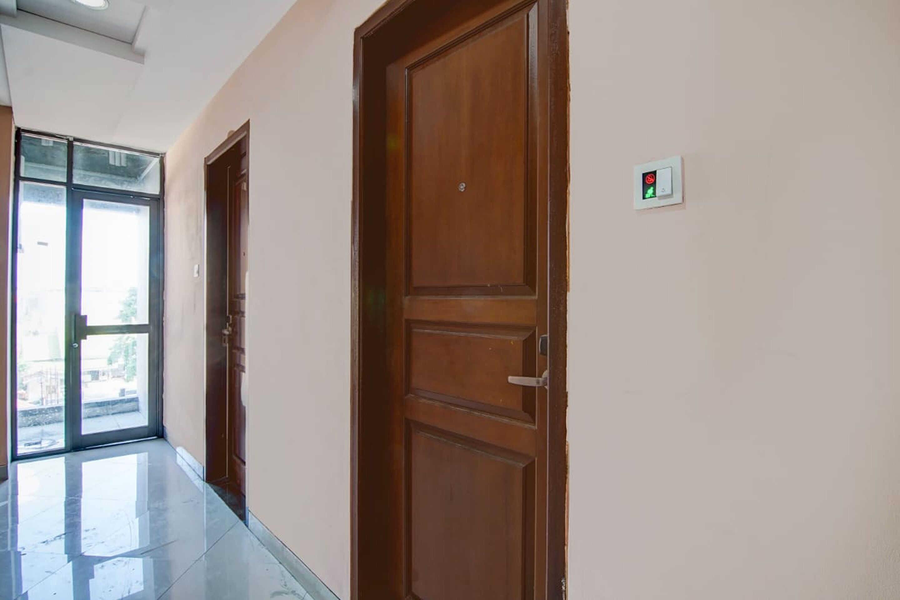 A hallway with wooden doors and a glass door leading outside.