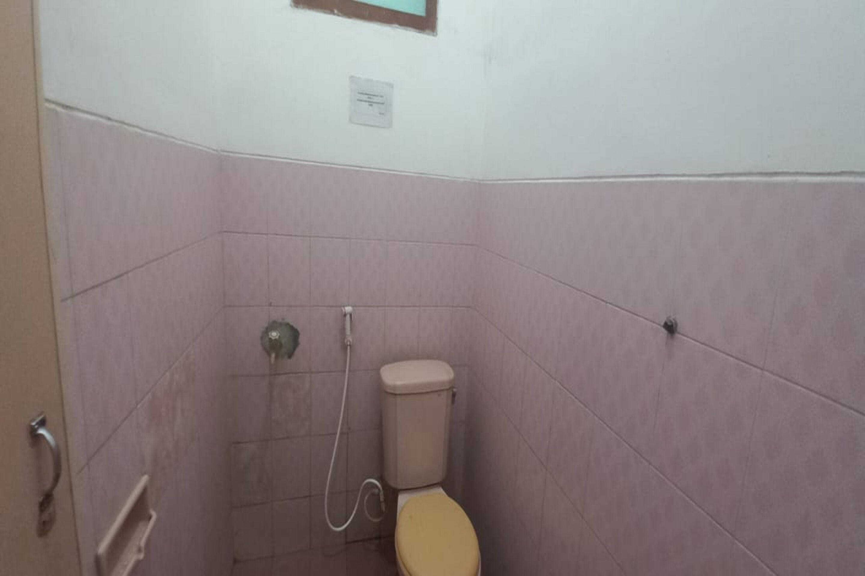 A small bathroom with a toilet, a shower, and a wall-mounted sink.