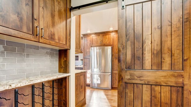 Una cucina con mobili in legno, un frigorifero in acciaio inossidabile e uno schienale piastrellato.
