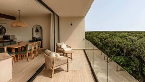 Ein Balkon mit Blick auf eine bewaldete Landschaft, ein Essbereich mit Holzmöbeln und ein modernes Interieur.