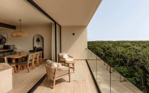 A balcony with a view of a forested landscape, a dining area with wooden furniture, and a modern interior design. - Kamaya Luna Tulum Samsara Beach Club Access (Tulum)