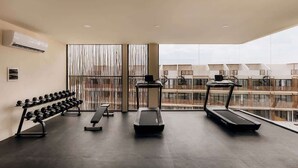 Ein Fitnessraum mit Laufbändern, Hanteln und einer Bank.