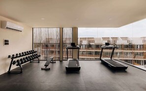 Une salle de sport équipée de tapis de course, d’haltères et d’un banc de musculation.