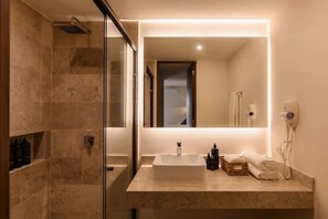 A modern bathroom with a glass shower enclosure, a large mirror, a sink, and a hairdryer on the wall. - Kamaya Luna Tulum Samsara Beach Club Access (Tulum)