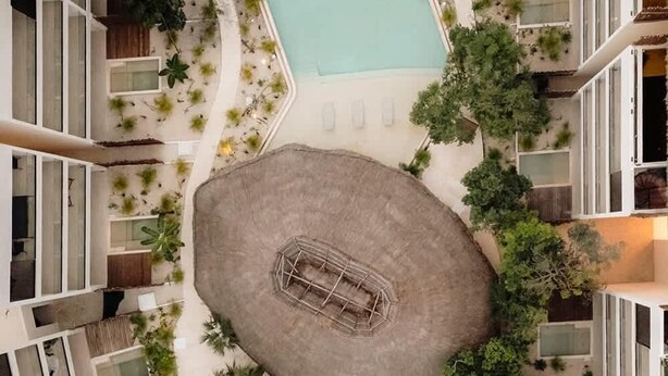 Ein Poolbereich auf dem Dach mit zwei Pools, einer Sitzgruppe in der Mitte und umliegender Bepflanzung.