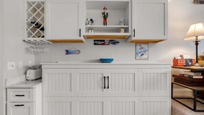 Una cocina con armarios blancos, una estantería para vinos, un tazón azul y una figurita pequeña.