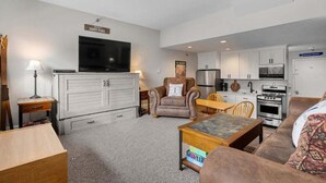 Una sala de estar con televisión, chimenea, comedor y cocina.