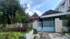 A residential area with a gated entrance, a concrete pathway, and greenery. - OYO 95055 Homestay Panasan Pak Budi (Sambi)