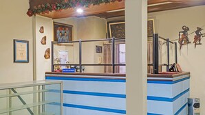 A reception area with a counter, framed certificates, and decorative wall art. - OYO 95055 Homestay Panasan Pak Budi (Sambi)