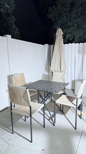 An outdoor patio with a white fence, a table, and four chairs.