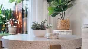 Una mesa redonda con una planta en maceta y una pila de posavasos.