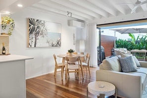 A modern interior with a dining area, a sofa, and a view of the outdoors. - Noosa River 2BD Townhouse - Modern & Stylish (Noosa)