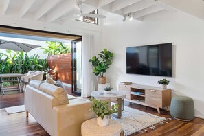 A modern living room with a sofa, TV, and plants. - Noosa River 2BD Townhouse - Modern & Stylish (Noosa)