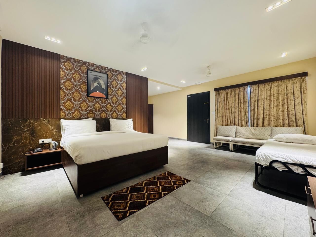 Une chambre d’hôtel moderne équipée d’un grand lit, d’un lit plus petit, d’un canapé et d’un bureau.