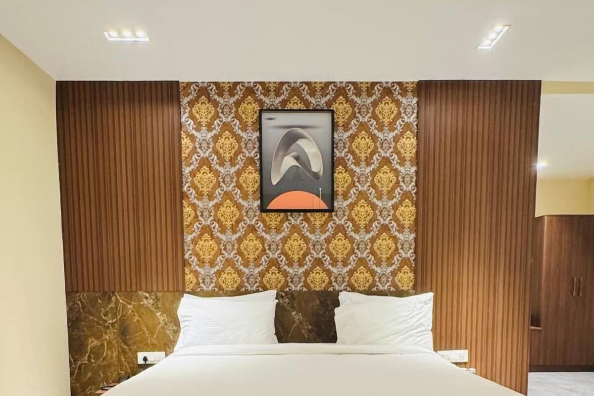 Een slaapkamer met een groot bed, een behang met patroon en een lijst met een afbeelding erboven.