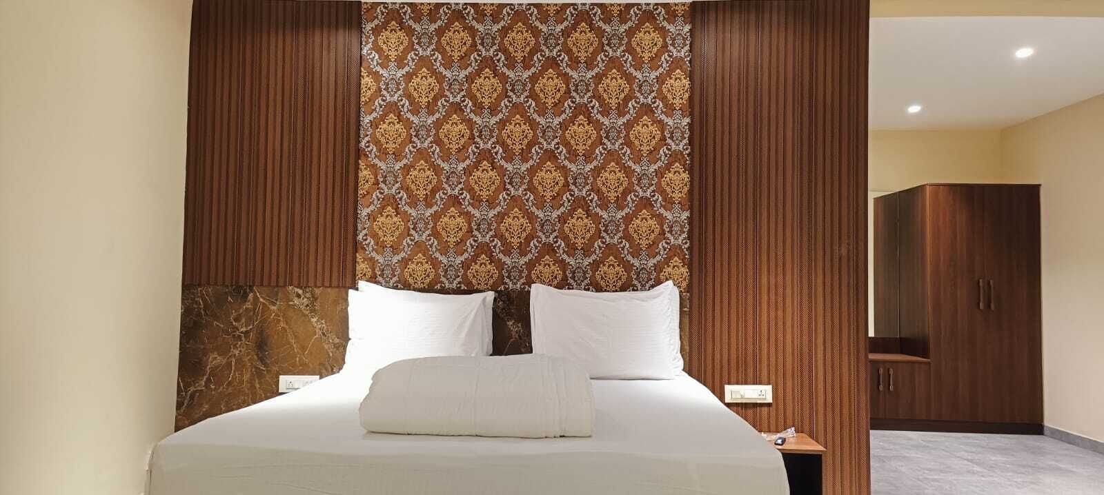 Una habitación de hotel con una cama grande, cabecero de madera y pared con diseño.