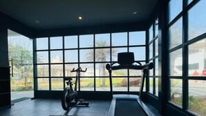 Een fitnessruimte met een loopband, hometrainer en elliptische trainer.