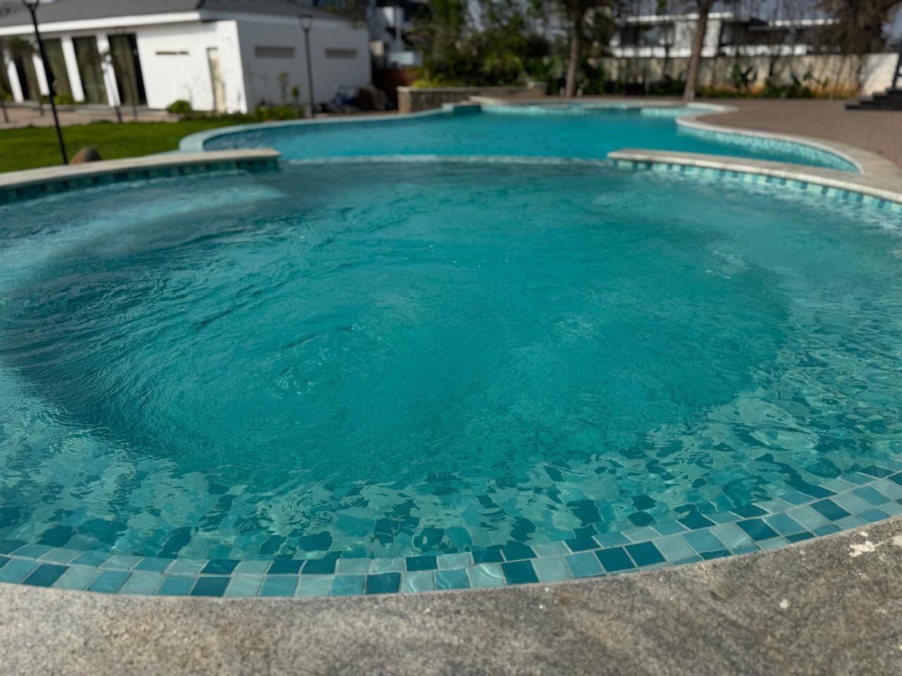 Une piscine avec un bord carrelé et une promenade qui l’entoure.