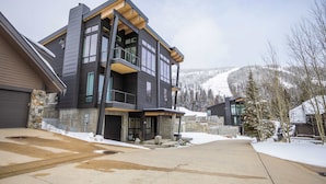 A modern two-story house with a stone foundation, large windows, and a covered front porch. - OutWest Idaho Ski Condo (Sandpoint)
