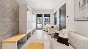 A modern living room with a wooden accent wall, a bench, a sofa, and a large window. - OutWest Idaho Ski Condo (Sandpoint)