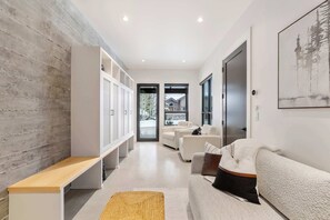 Ein modernes Wohnzimmer mit einer Holzwand, einer Bank, einem Sofa und einem großen Fenster.