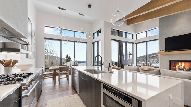 A modern kitchen with a large island, built-in appliances, and large windows offering a view of the outdoors. - OutWest Idaho Ski Condo (Sandpoint)