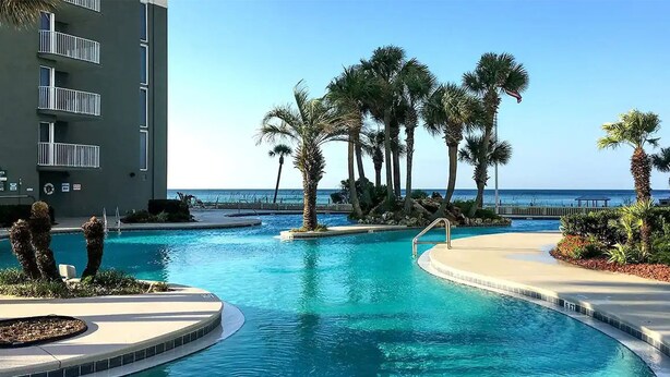 A swimming pool with palm trees and a view of the ocean.