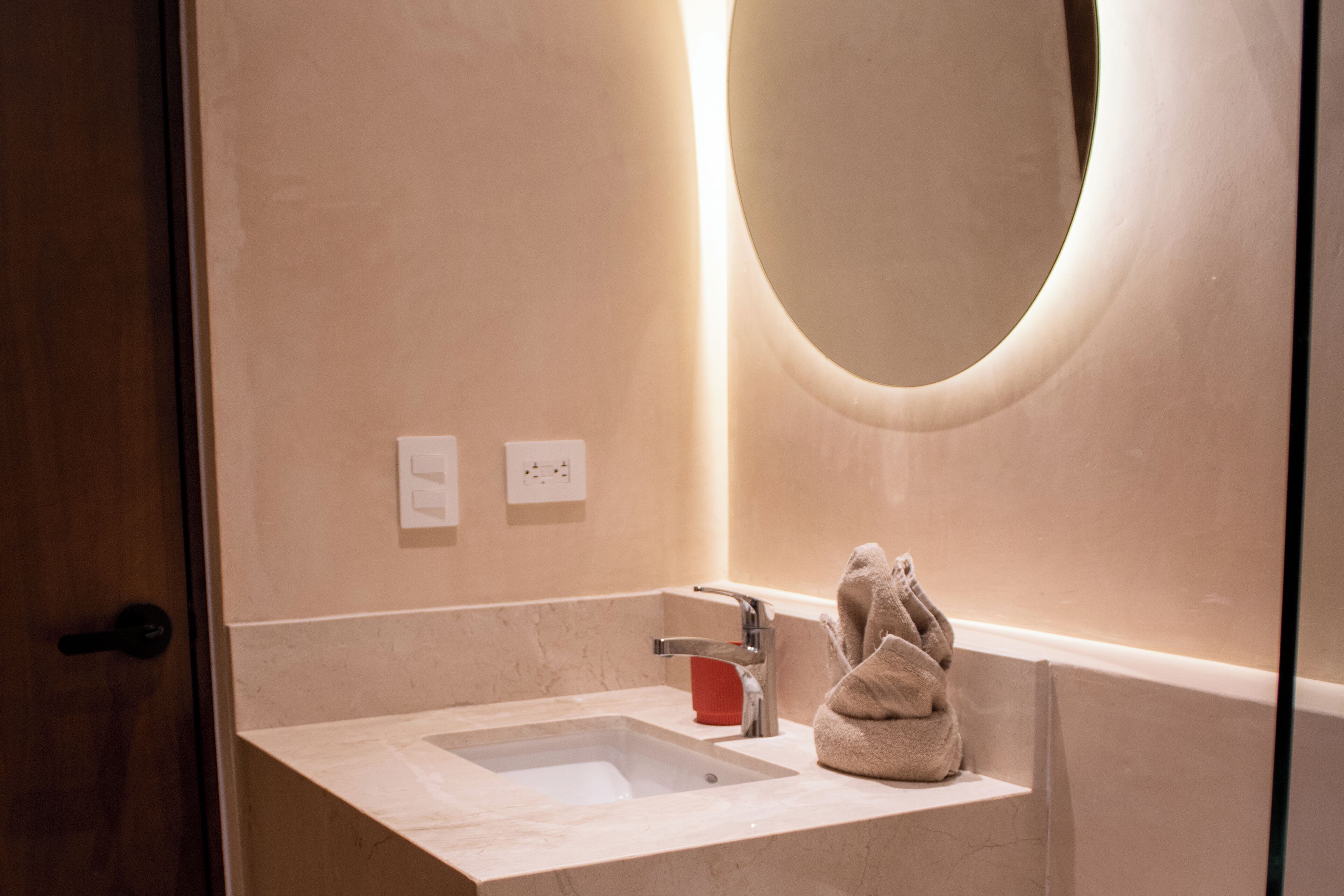 A bathroom with a marble sink, a towel, and a large mirror.