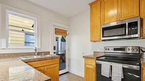 A kitchen with granite countertops, wooden cabinets, a stainless steel microwave, and an oven. - Charming and Spacious Seattle 3B3B Townhome (Seattle)