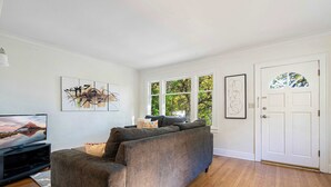 A living room with a sectional sofa, a flat-screen TV, and artwork on the walls. - Charming and Spacious Seattle 3B3B Townhome (Seattle)