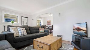 A modern living room with a grey sofa, a wooden coffee table, and a flat-screen TV. - Charming and Spacious Seattle 3B3B Townhome (Seattle)