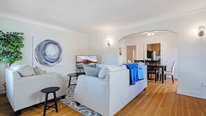 Ein modernes Wohnzimmer mit zwei Sofas, einem Couchtisch und einem Essbereich mit Tisch und Stühlen.